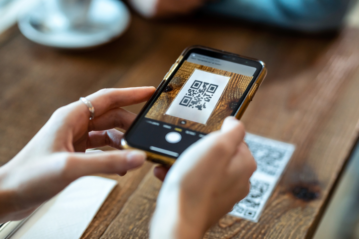 Close up of young woman hands using the smart phone to scan the qr code to select food menu in the restaurant.